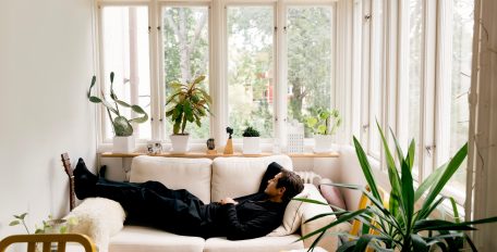 Ein Mann, der zu Hause im Wohnzimmer auf dem Sofa schläft, im Hintergrund ein Heizkörper