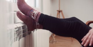 Die Füße einer Frau mit Socken auf einem Heizkörper