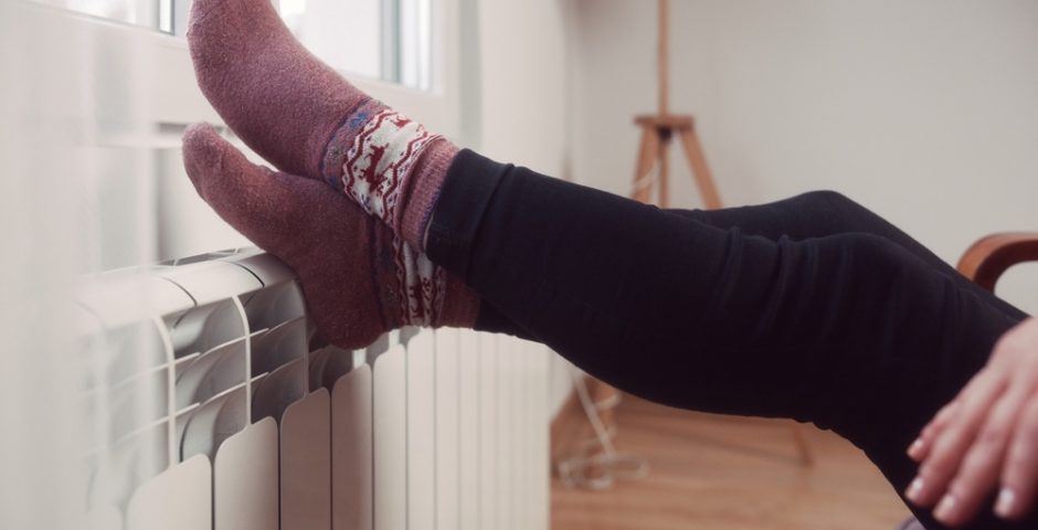 Die Füße einer Frau mit Socken auf einem Heizkörper