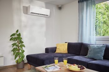 Ein Blick in ein Wohnzimmer mit einer dunklen Couch, an der Wand hängt ein Vaillant Klimagerät