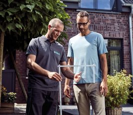 Ein Eigenheimbesitzer bespricht mit seinem Heizungsfachmann, wie eine energiesparende Heizung für das geplante Gewächshaus möglich ist.