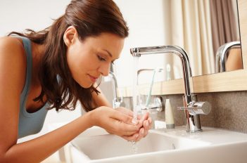 Morgens im Bad: Eine Frau fängt mit ihren Händen das wohltuende Nass aus dem Wasserhahn auf.