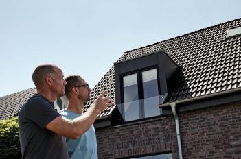 Zwei Männer schauen an einem modernen Wohnhaus empor.