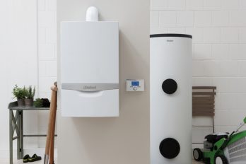 In einer Kellernische steht ein Warmwasserspeicher, daneben hängt ein Gas-Brennwertgerät an der Wand.