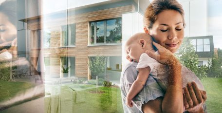 Eine junge Frau hält ihr Baby liebevoll im Arm. Besonders Säuglingen machen hohe Raumtemperaturen durch Sommerhitze zu schaffen.