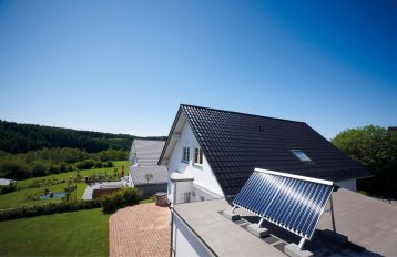 Solarkollektoren sind auf dem Garagendach neben einem Einfamilienhaus aufgeständert.