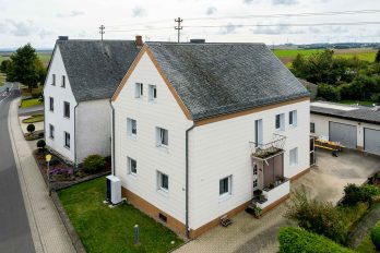 Das Bild zeigt ein dreistöckiges Einfamilienhaus in einer ländlichen Region.