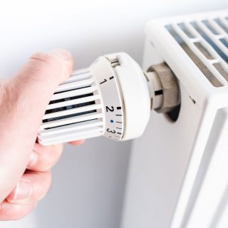 Person, die das Thermostat des Heizkörpers ausschaltet