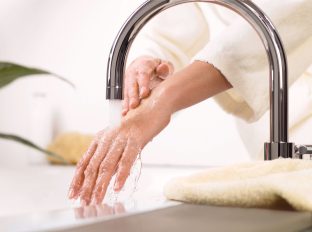 Eine Frau wäscht die Hände unter einem Wasserhahn.