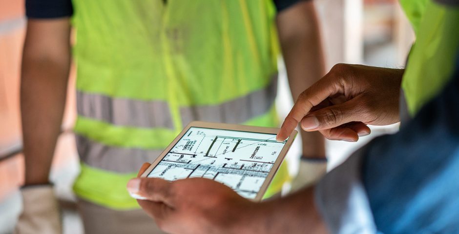 Baustelleningenieur überprüft Blaupausen auf digitalem Tablet