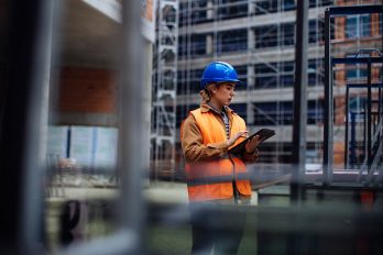 Junge Arbeiterin mit ihrem digitalen Tablet auf einer Baustelle