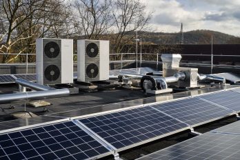 Auf dem Dach eines neuen Mehrfamilienhauses sind zwei Wärmepumpen und viele PV-Elemente installiert.