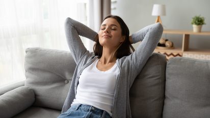 Junge Frau entspannt zuhause auf dem Sofa.