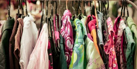 Verschiedene bunte Kleidungsstücke hängen auf einer Kleiderstange