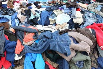 Ein Haufen unsortierter Kleidung mit verschiedenen Jacken, Hosen und Hemden in diversen Farben und Materialien