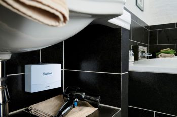 Unter einem Waschtisch im Bad ist ein sehr kompakter elektrischer Durchlauferhitzer für die Warmwasserbereitung montiert.