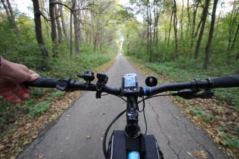 Nahaufnahme vom Lenkrad eines Fahrrads beim Fahren auf einem Waldweg