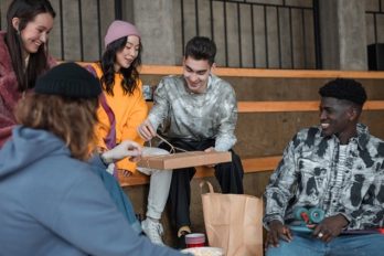 Eine Gruppe von Jugendlichen mit unterschiedlichen Hautfarben sitzt zusammen 