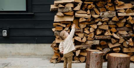 Kind vor einem Holzstapel