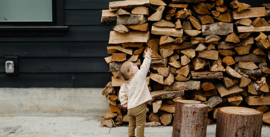 Kind vor einem Holzstapel