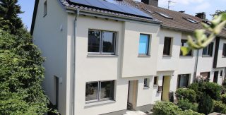 Das Bild zeigt ein saniertes, zweigeschossiges Reihenendhaus in Köln mit PV-Modulen auf dem Dach