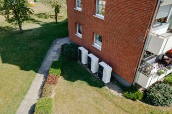 Das Bild zeigt ein Hochhaus aus den 60er Jahren mit einer Wärmepumpen-Kaskade