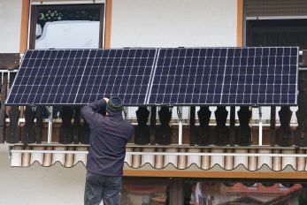 Ein Mann montiert ein Balkonkraftwerk zur Gewinnung von Strom