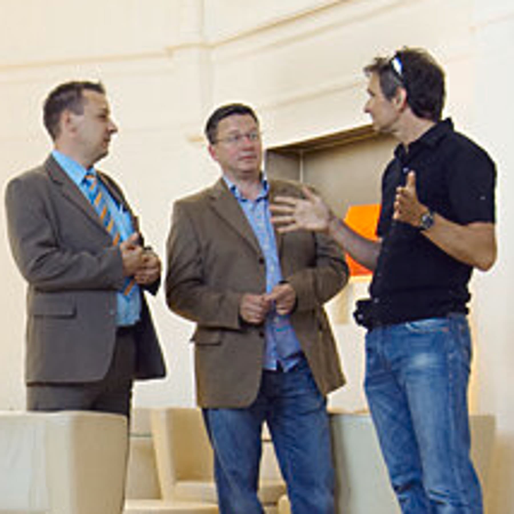 Drei Männer stehen beisammen und unterhalten sich angeregt