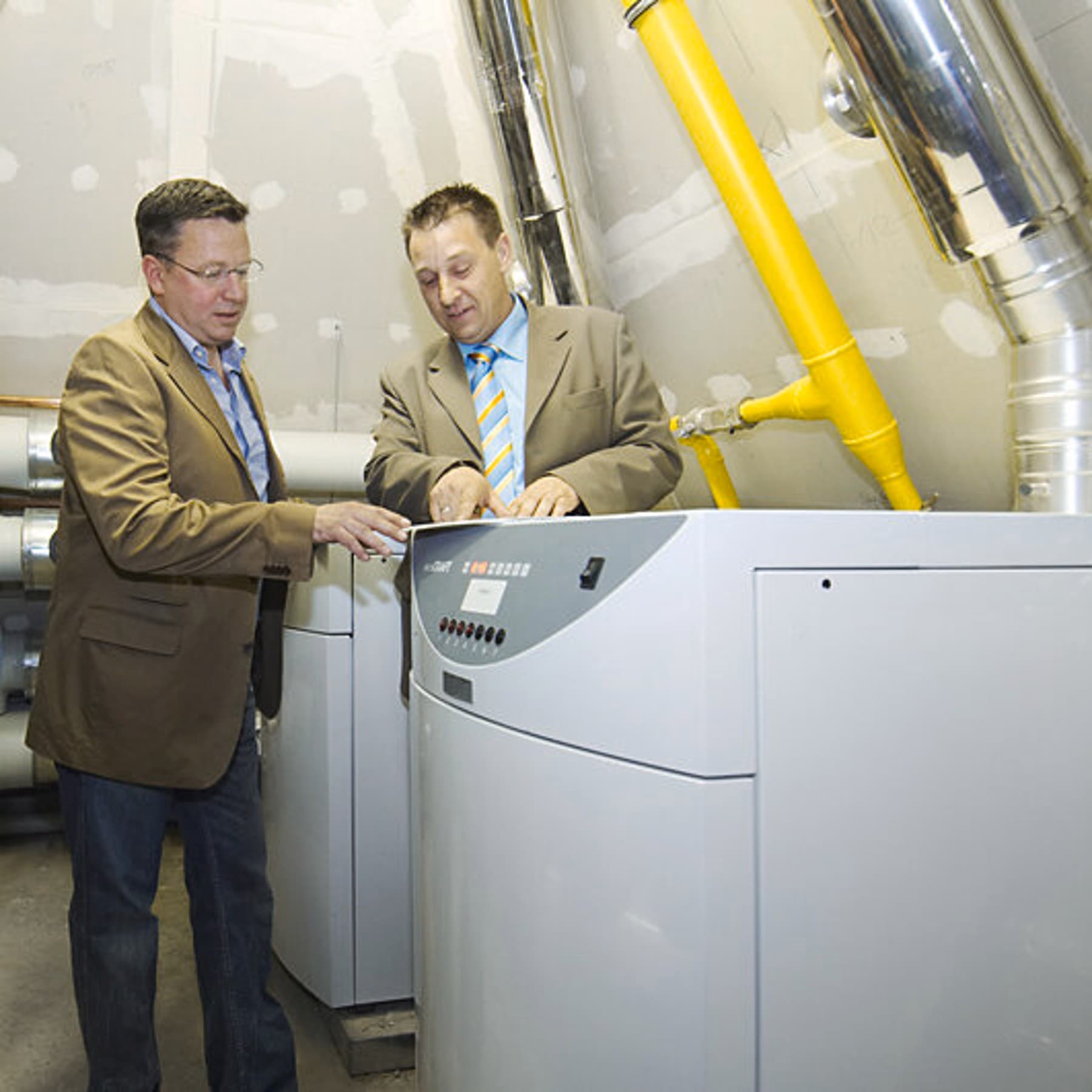 Zwei Männer stehen im Heizungsraum der Kirche neben der Heizung