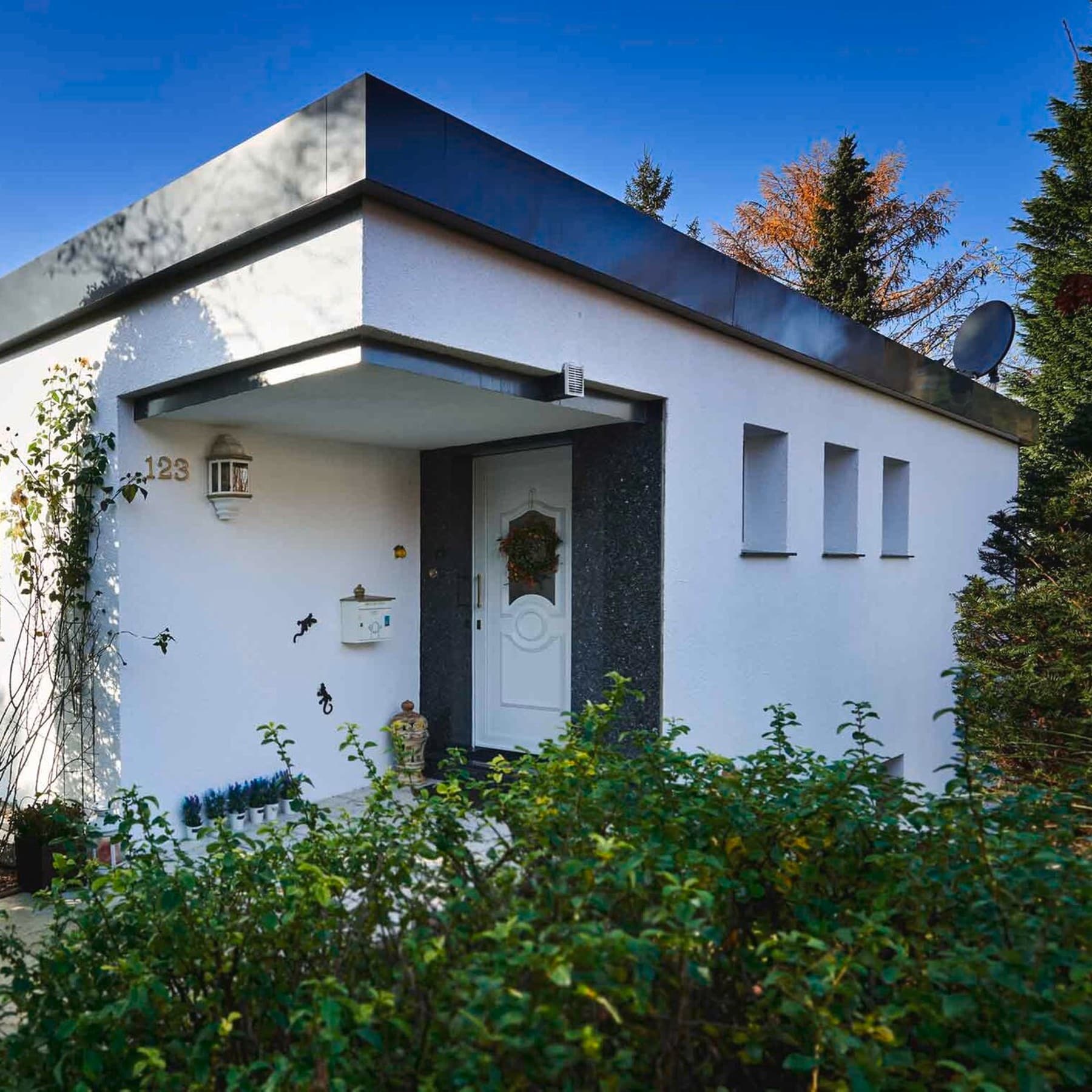 Frontansicht eines Flachdachbungalows mit Fokus auf den Hauseingang