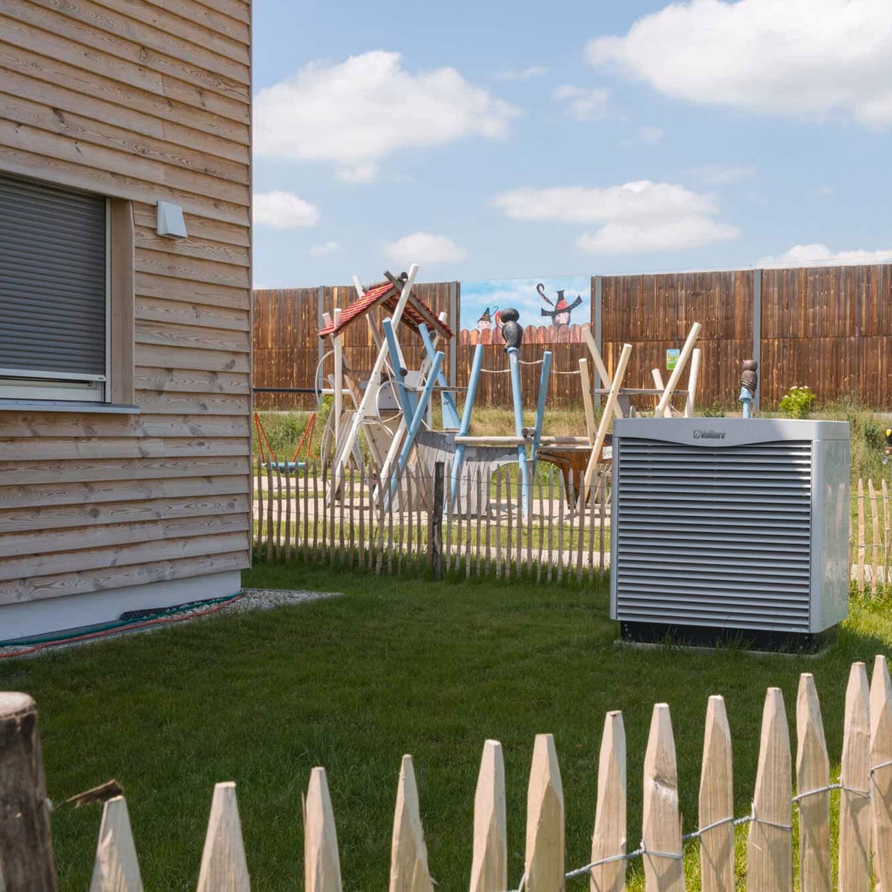 Wärmepumpe im Garten eines Holzhauses