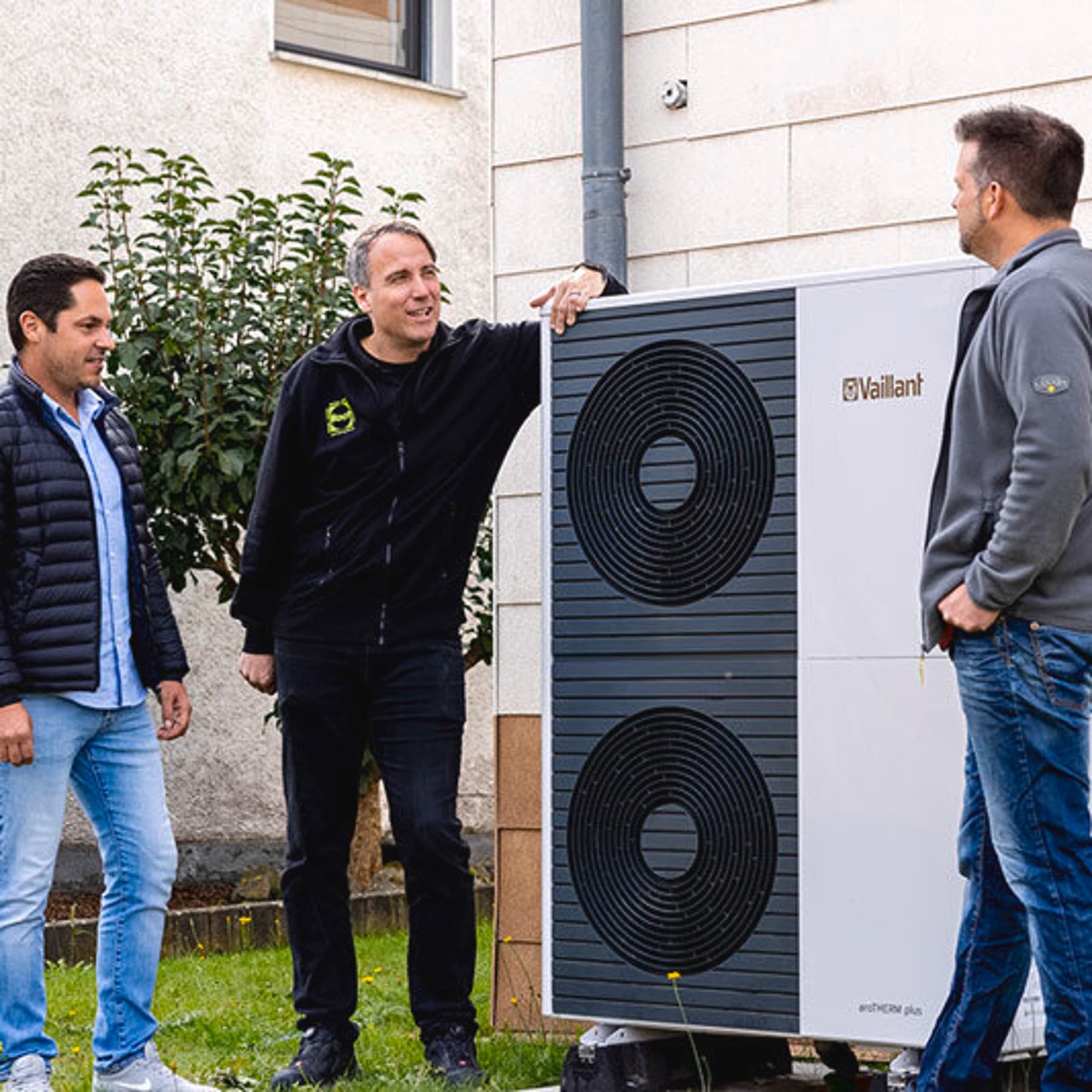 Drei Männer stehen vor der Wärmepumpen-Außeneinheit