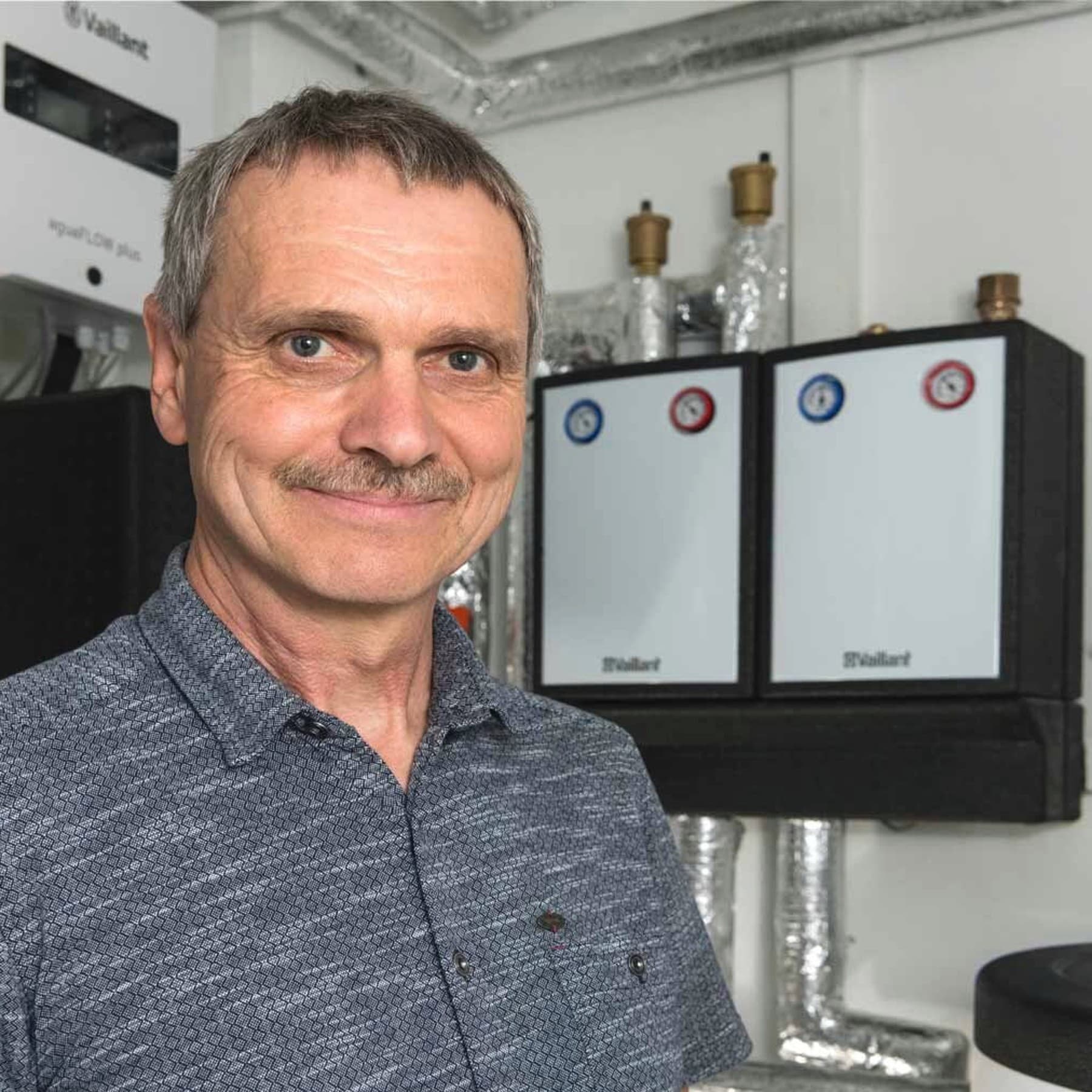 Portraitfoto des Heizungsbauers vor den Vaillant Geräten