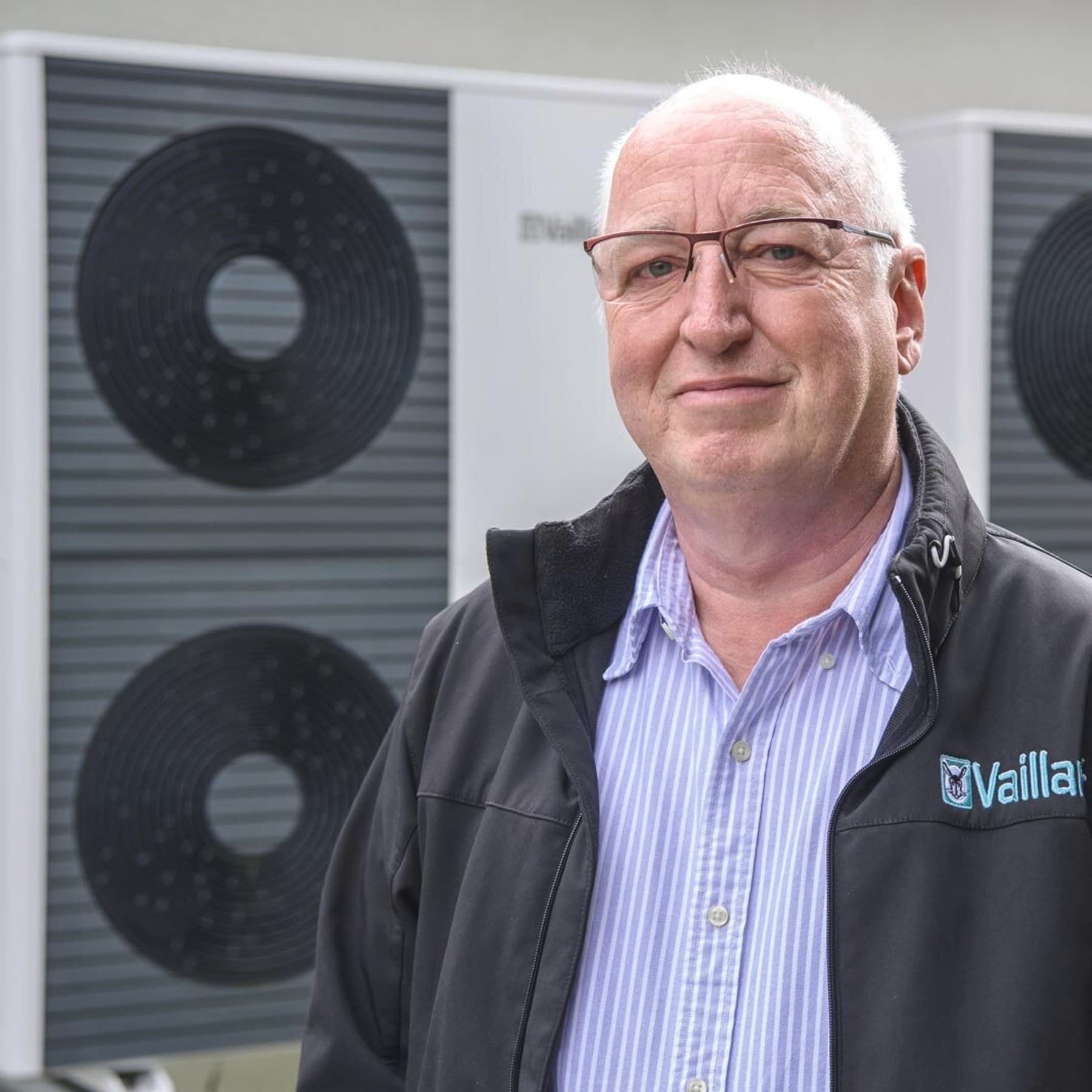 Vaillant Vertriebsingenieur steht vor den Außeneinheiten der Wärmepumpen-Kaskade