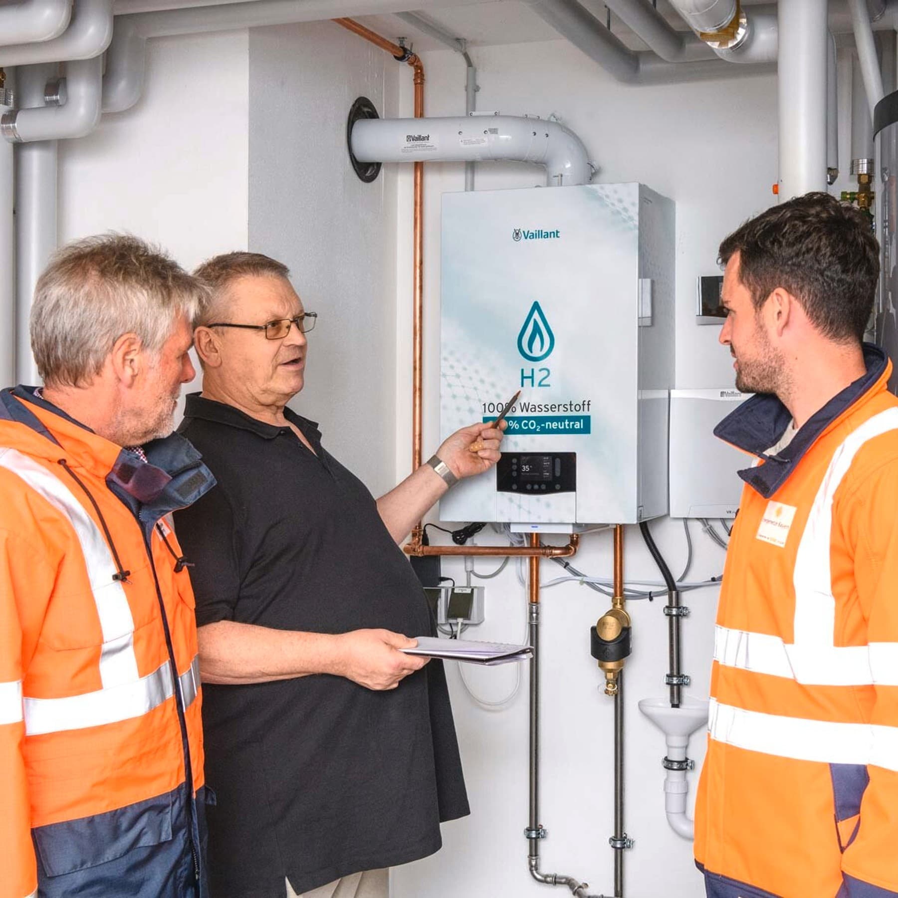 Mehrere Personen, die sich vor dem Vaillant Wasserstoff Heizgerät unterhalten