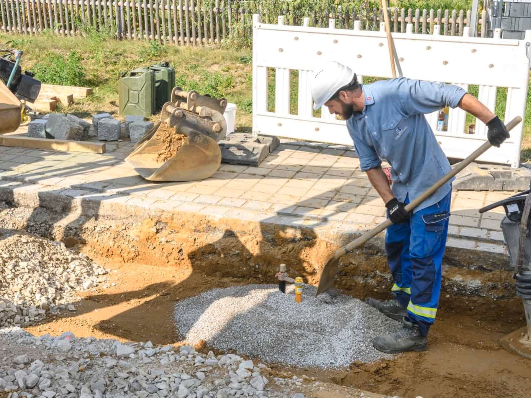 Person beim Verteilen eines Kieshaufens mit einer Schuafel