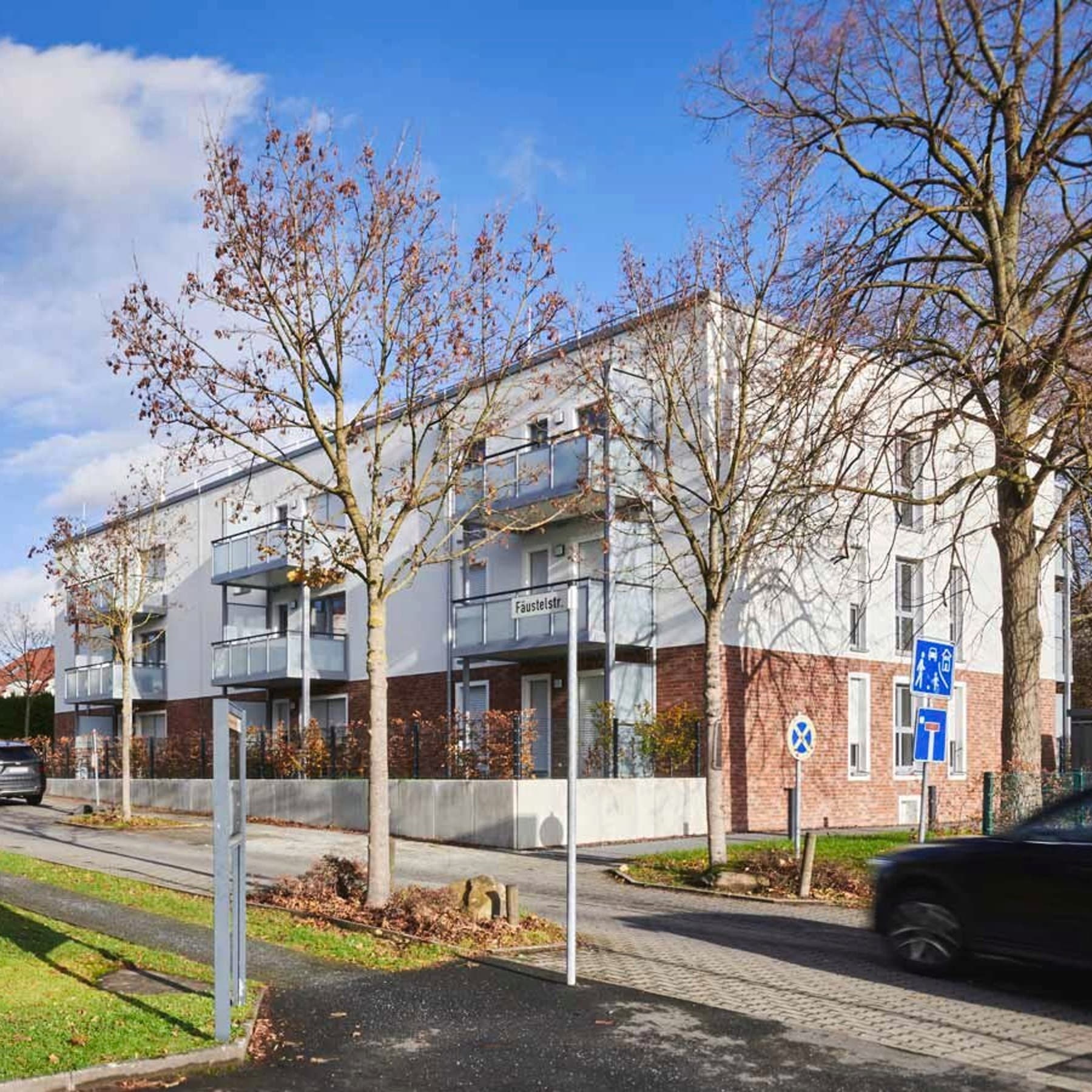 Seitenansicht des neuen Mehrfamilienhauses von der gegenüberliegenden Straßenseite