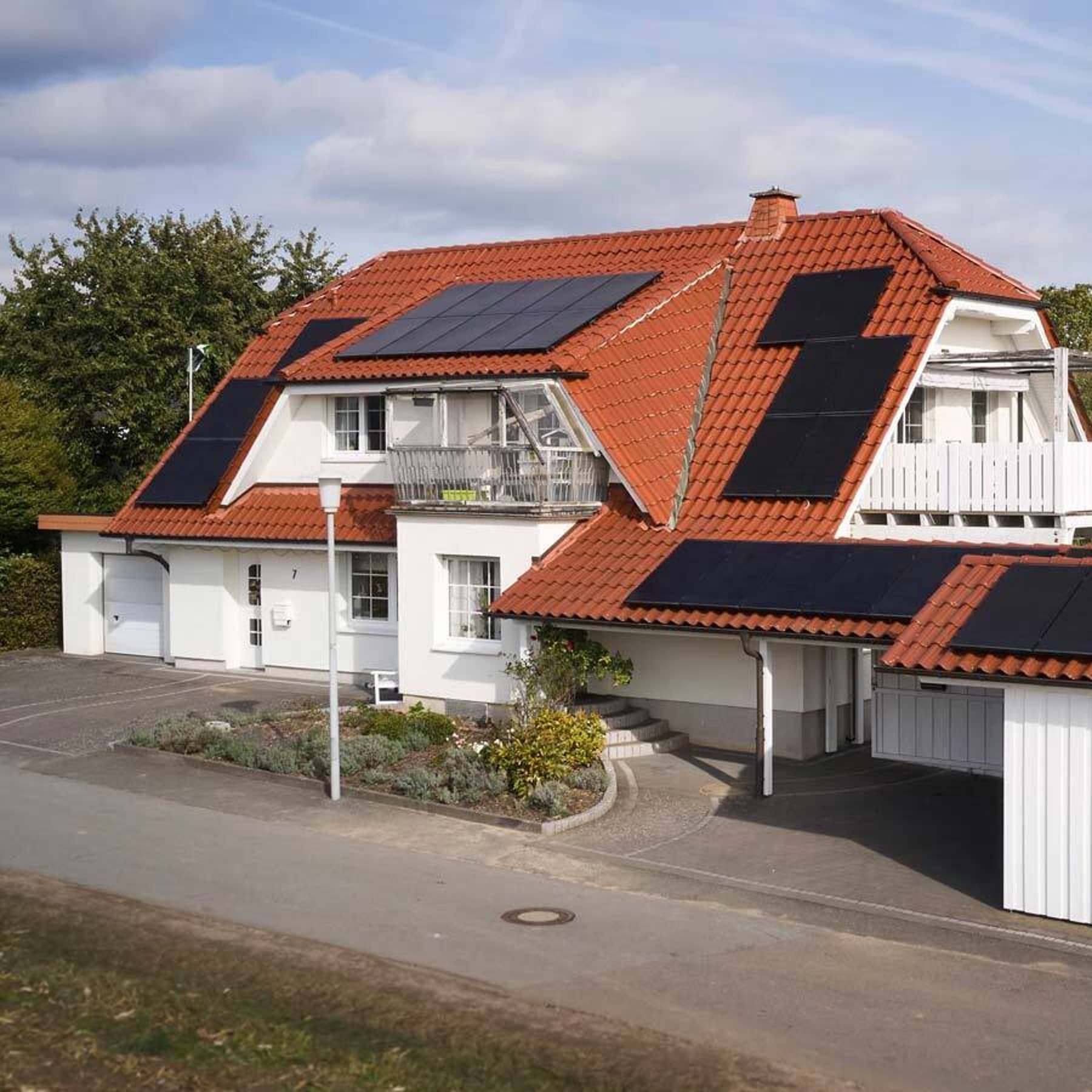Zweifamilienhaus mit Photovoltaik auf dem Dach, im Vordergrund ein integrierter Carport