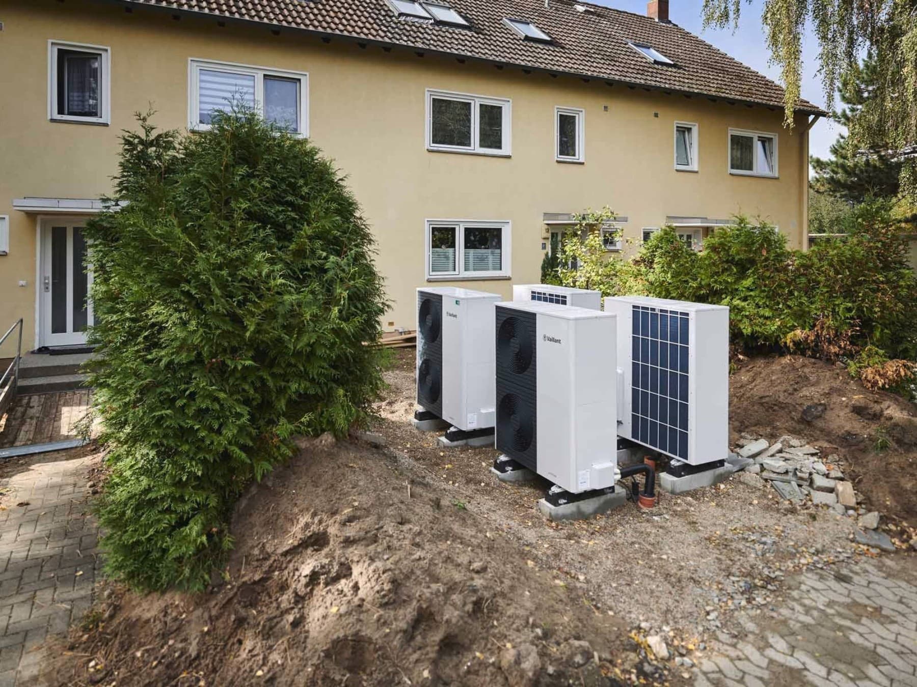 Frontansicht eines weiteren Reihenhauses mit mehreren Wärmepumpen davor