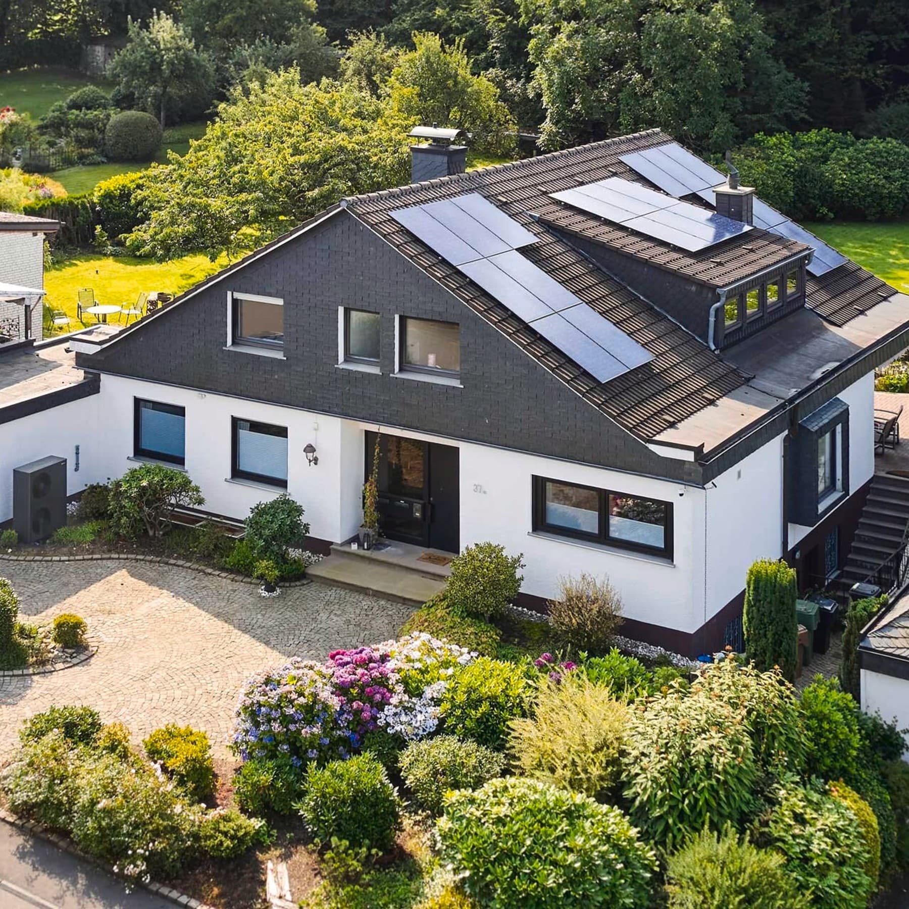 Außenansicht des Hauses mit einer schwarzgrauen Vaillant Wärmepumpe und PV auf dem Dach