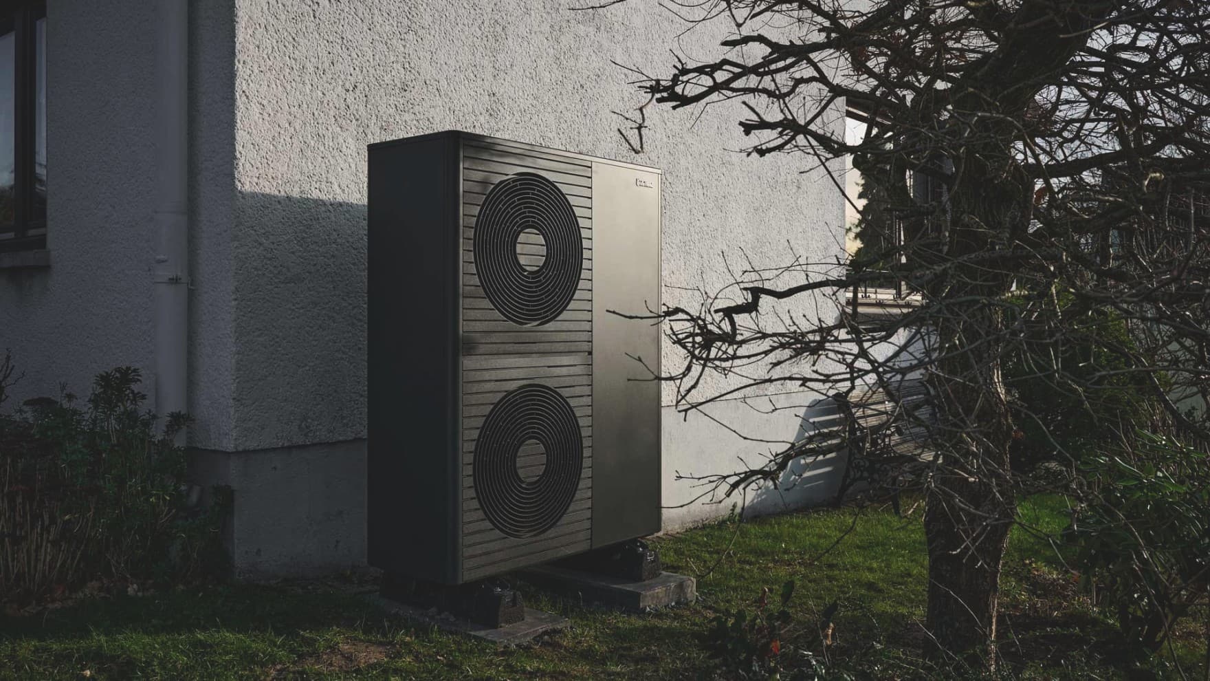 Doppelstöckige Wärmepumpe aroTHERM plus im Vorgarten vor weißer Hauswand