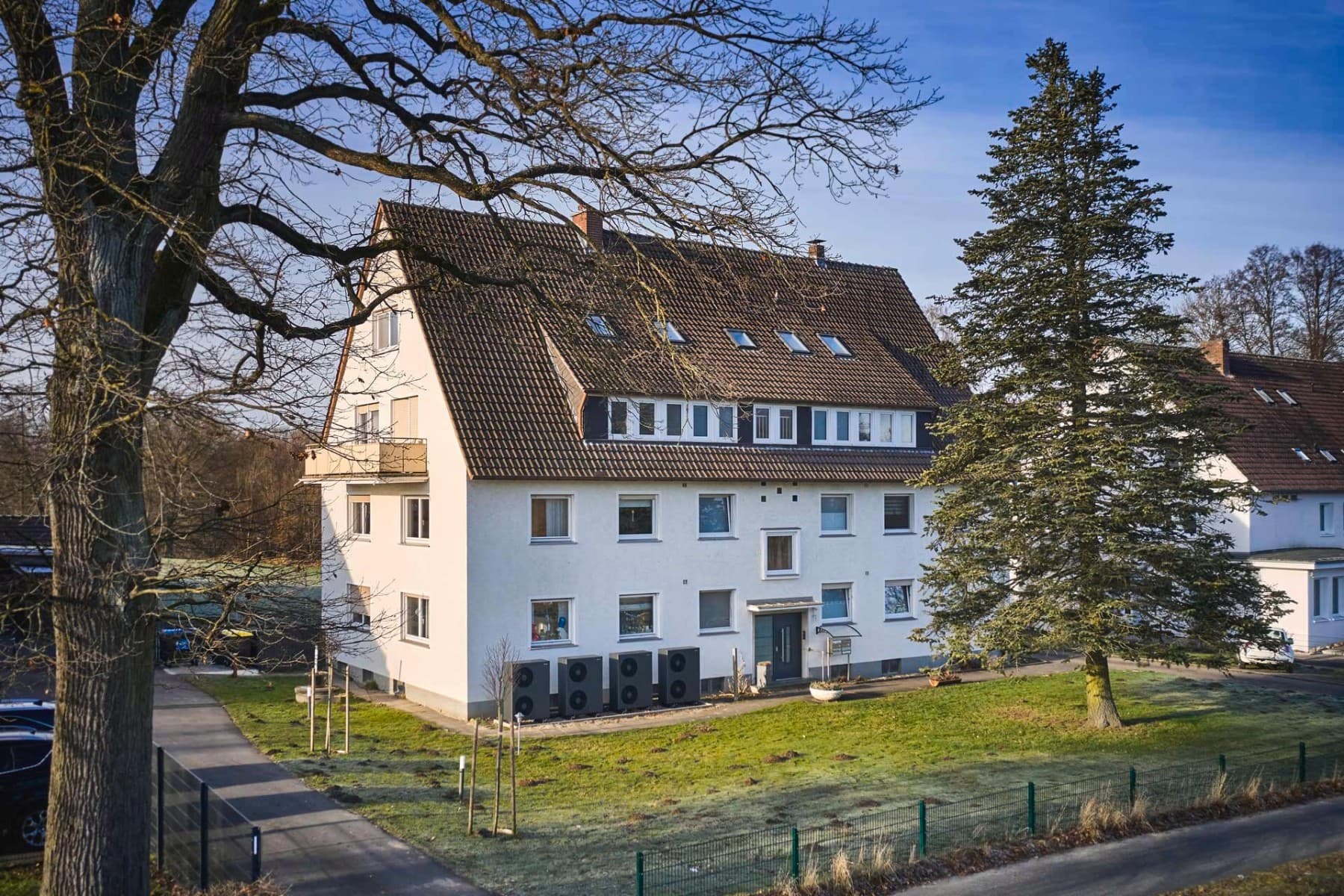 Mehrfamilienhaus mit Wärmepumpen davor