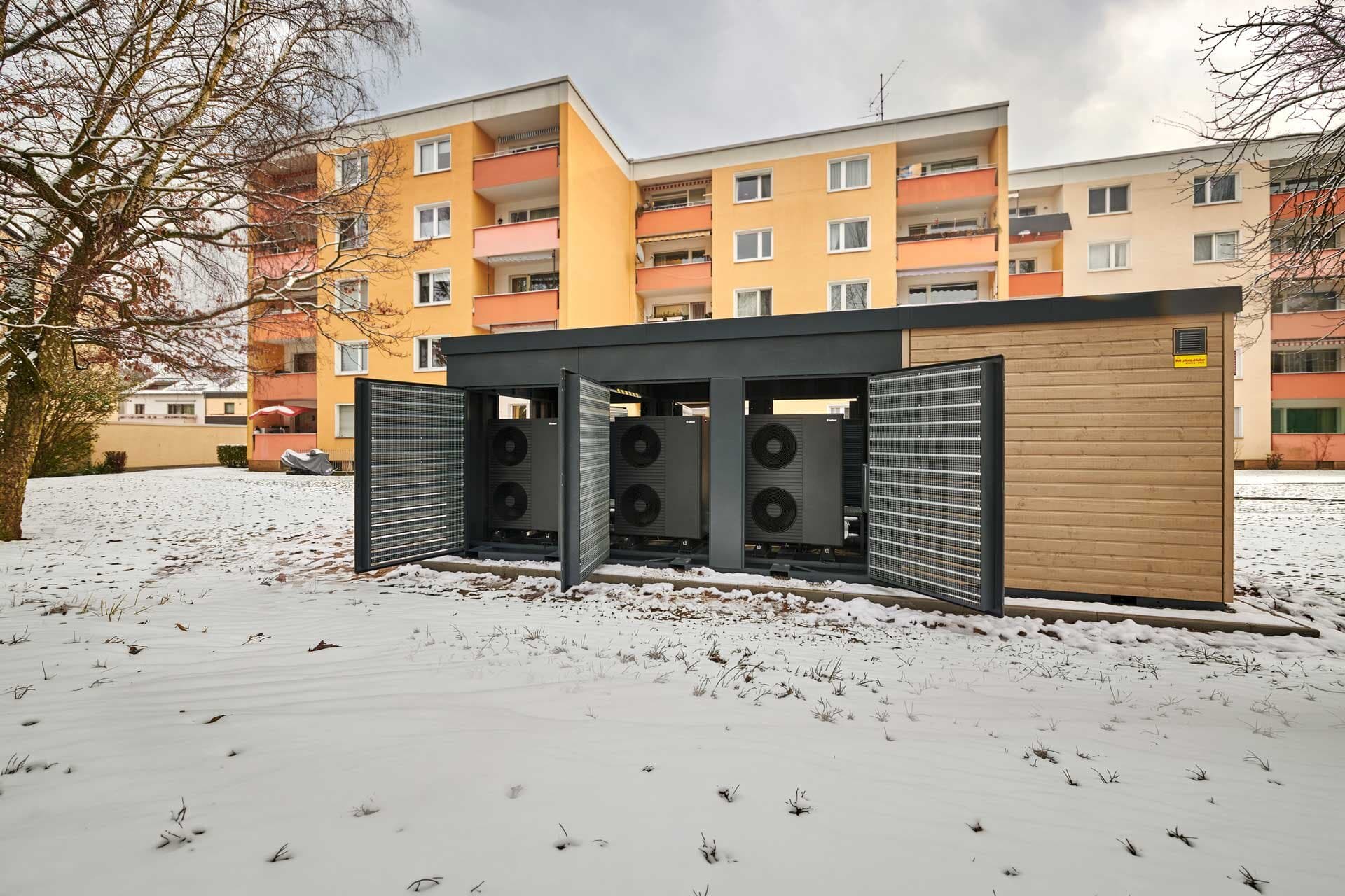 Energy Unit 2.0 bestehend aus einer Wärmepumpenkaskade steht vor den Mehrfamilienhäusern
