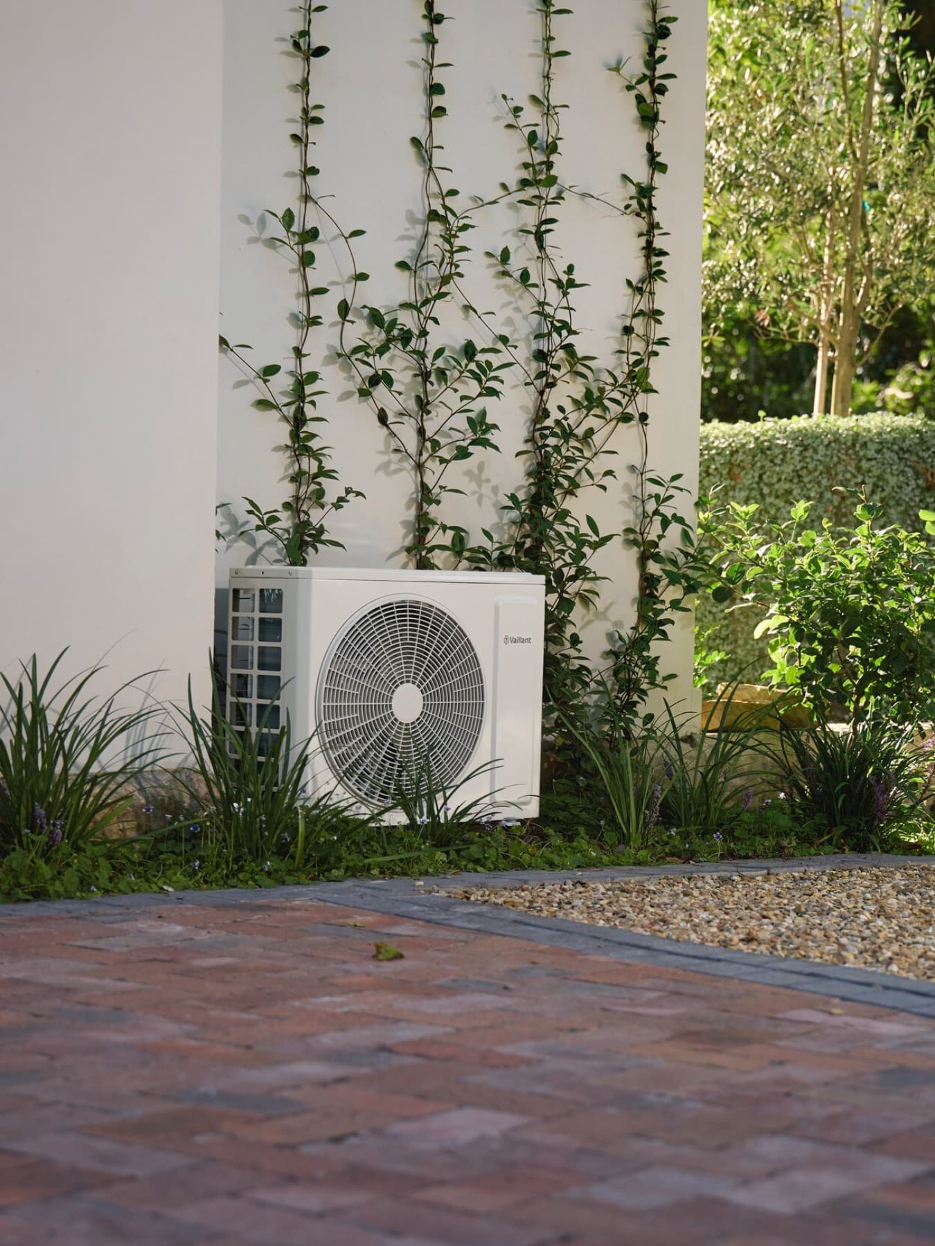 Außengerät der Mono-Split-Klimaanlage climaVAIR plus von Vaillant im Garten vor einer Hauswand