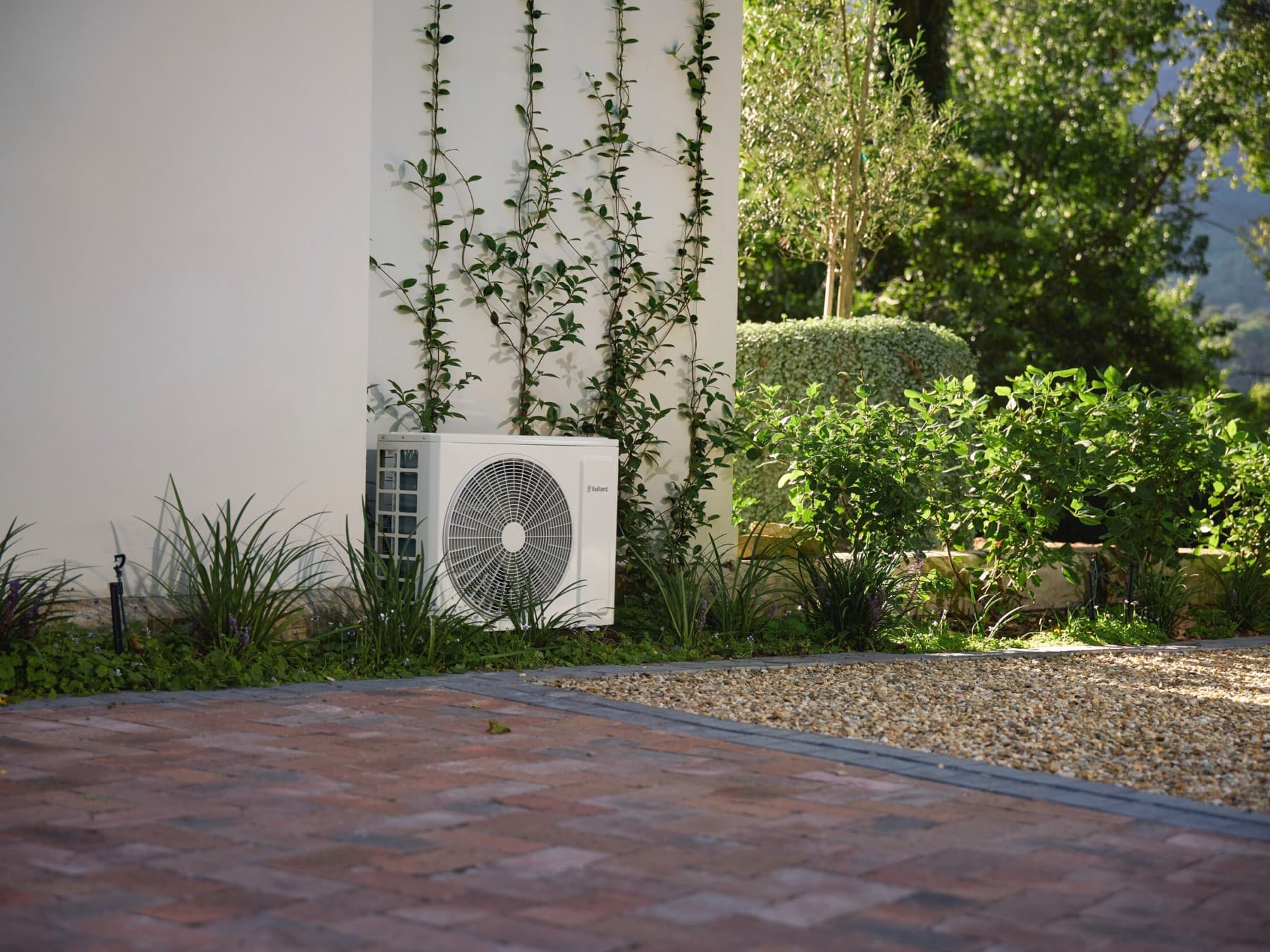 Außengerät der Mono-Split-Klimaanlage climaVAIR plus von Vaillant im Garten vor einer Hauswand