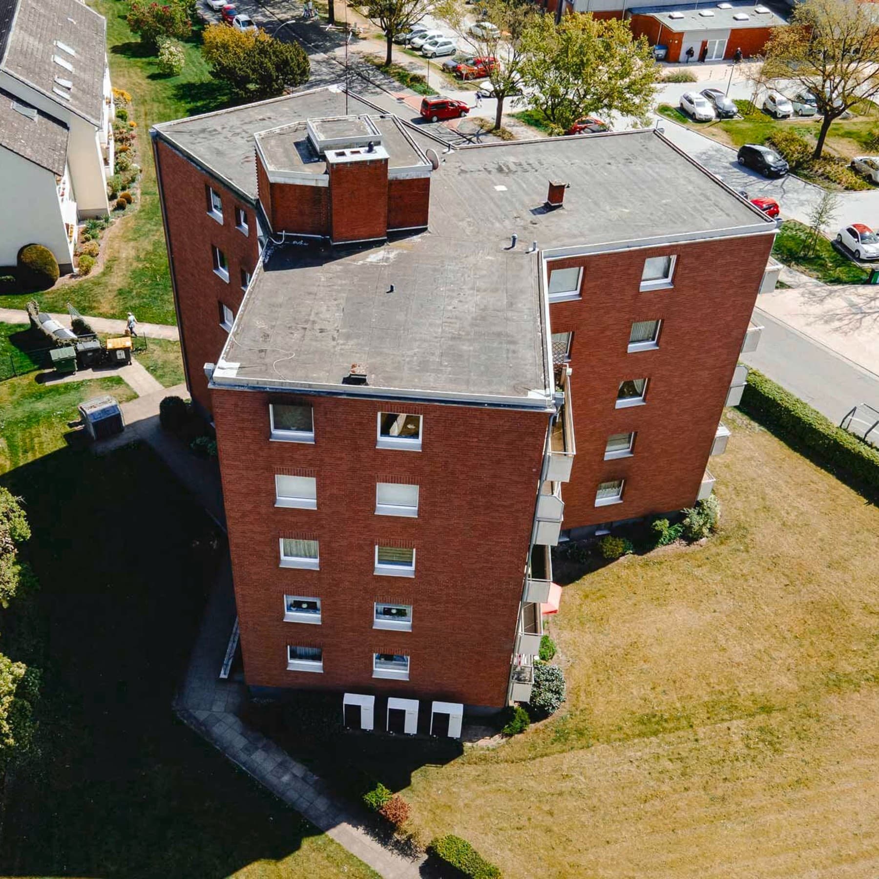 Ein großes Mehrfamilienhaus mit Grünfläche von oben.