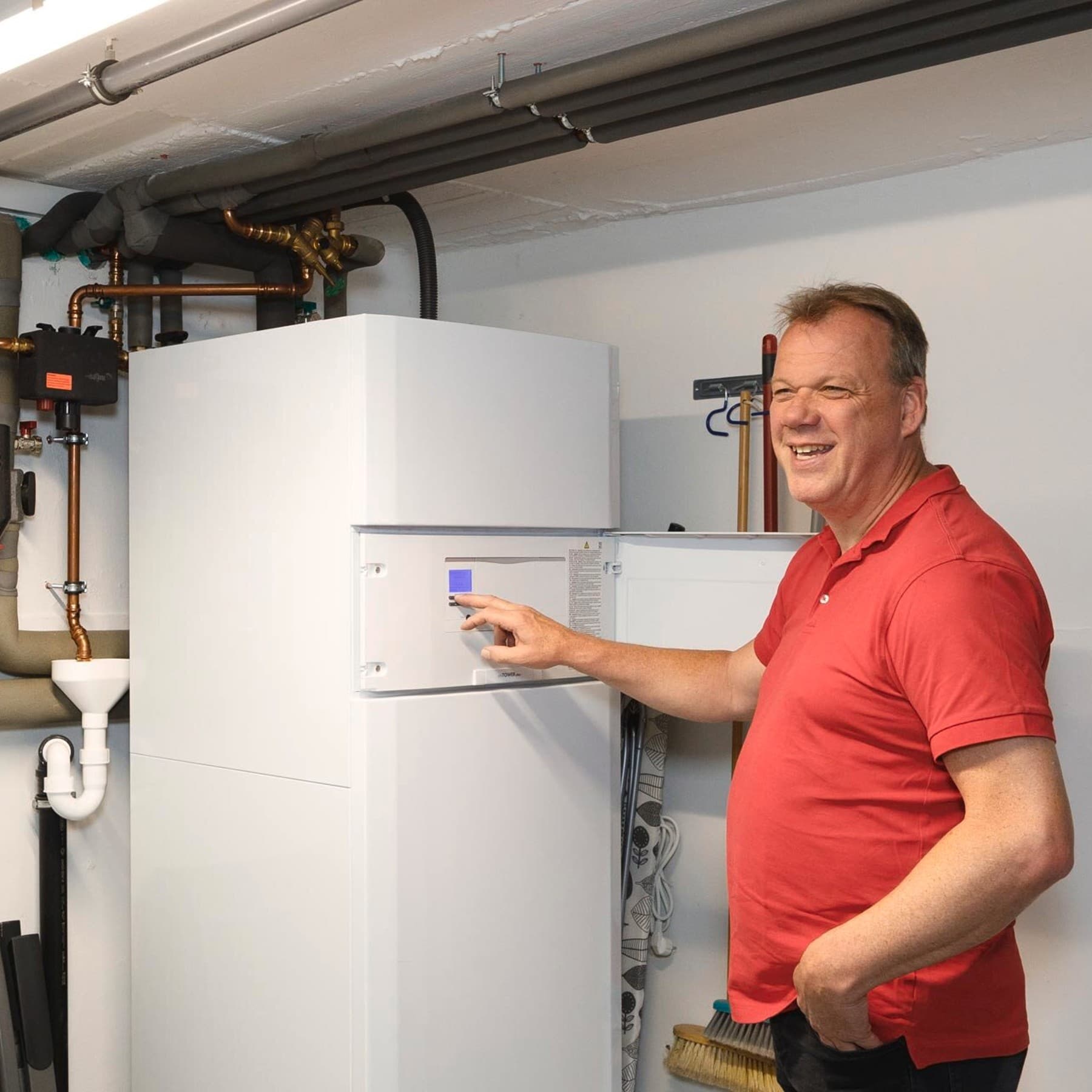 Foto des Hausbesitzers vor seiner Wärmepumpen Inneneinheit im Heizungskeller