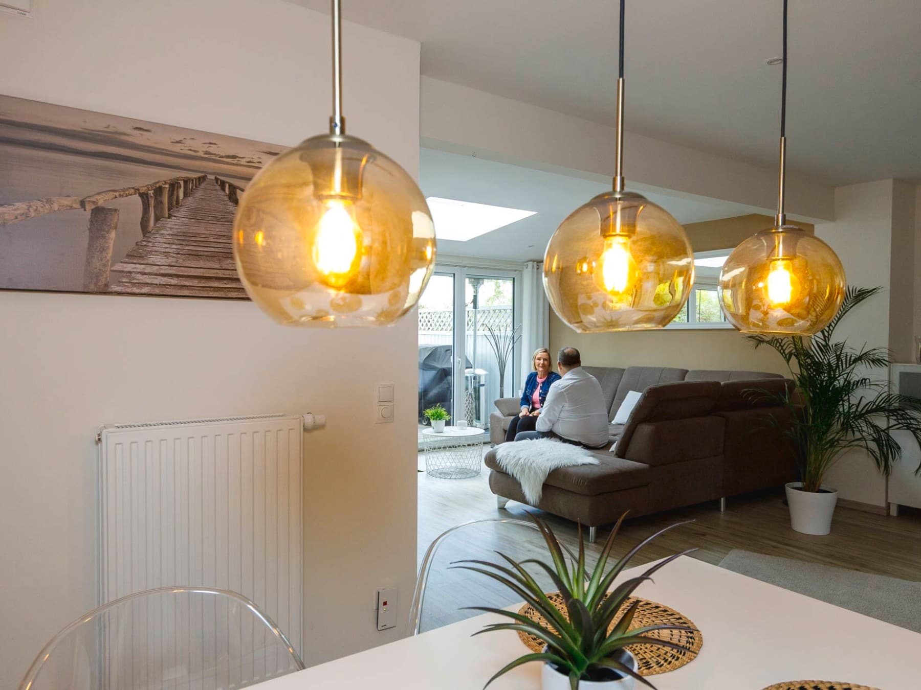 Esszimmer mit Radiatoren und zwei Personen im Hintergrund auf der Couch