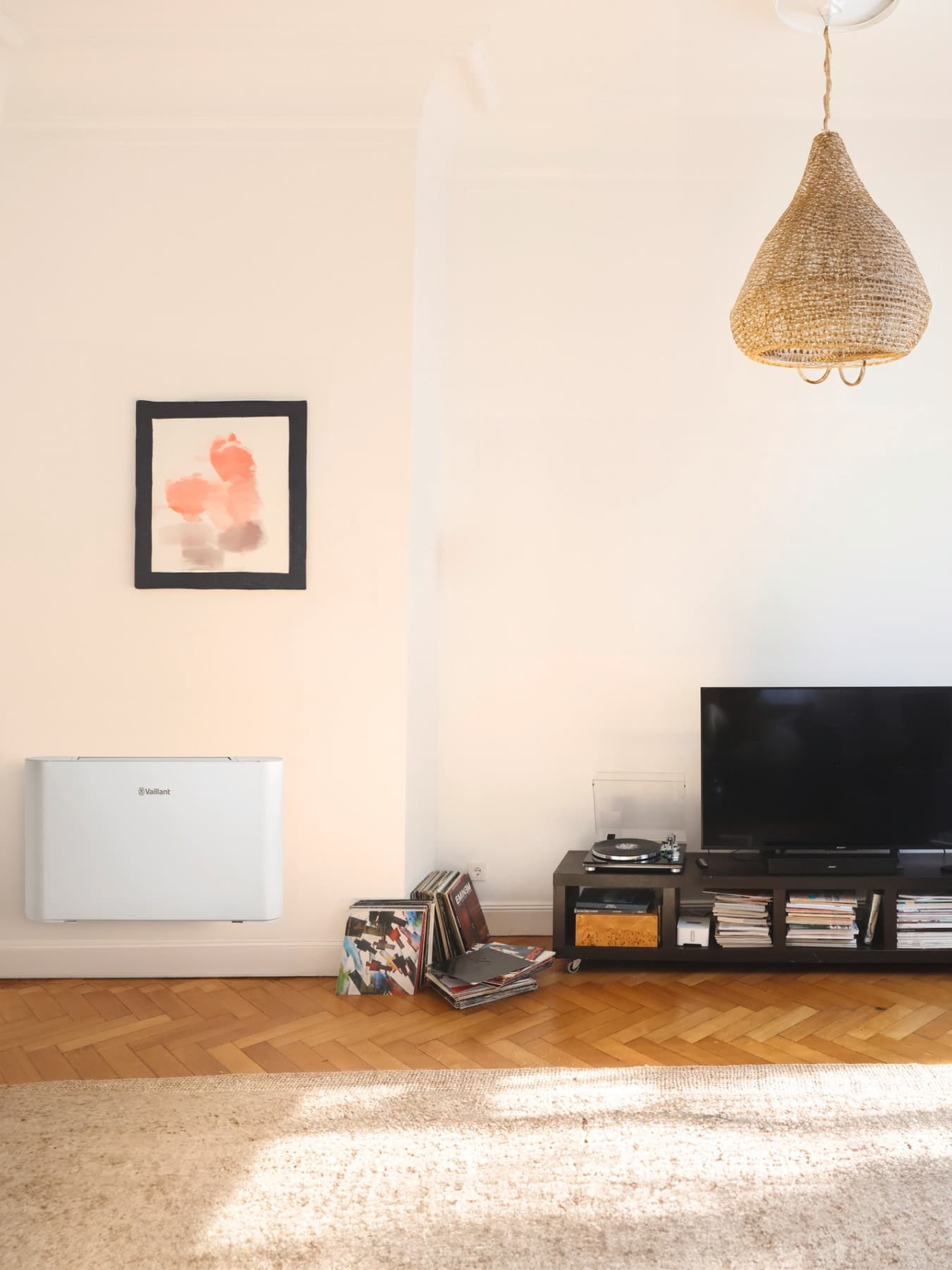 Ein Vaillant Gebläsekonvektor hängt an einer Wand im Wohnzimmer neben einen TV Board.