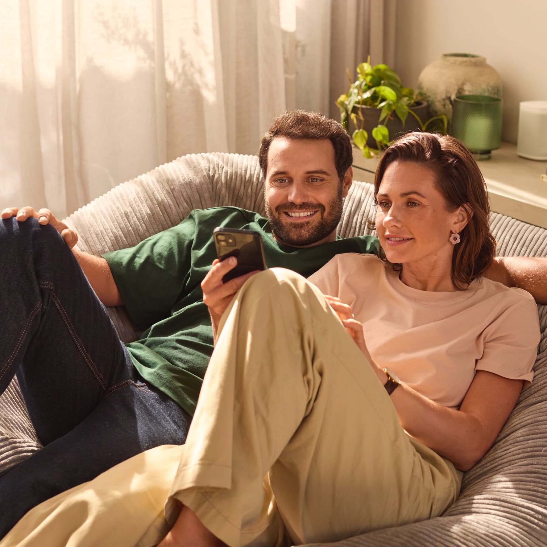 Paar sitzt auf dem Sofa und blickt auf ein Smartphone